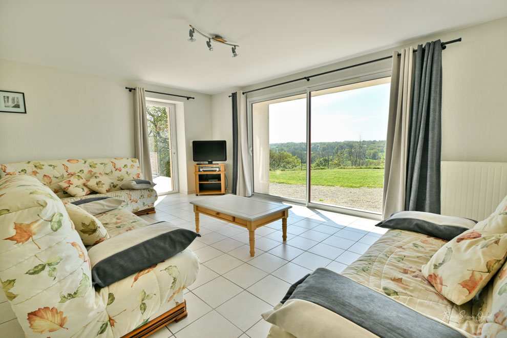 Salle de séjour avec grande baie vitrée et vue sur la vallée